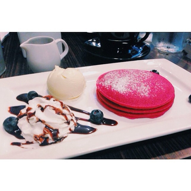 Red velvet pancakes with cream cheese topping on the side.