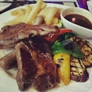 Mixed grill of sausage, steak, lamb chop and grilled vegetables.