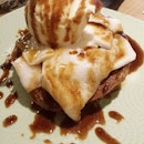 Homemade Coconut Pancakes topped with fresh coconut meat and coconut ice cream drizzled with salted caramel sauce.
